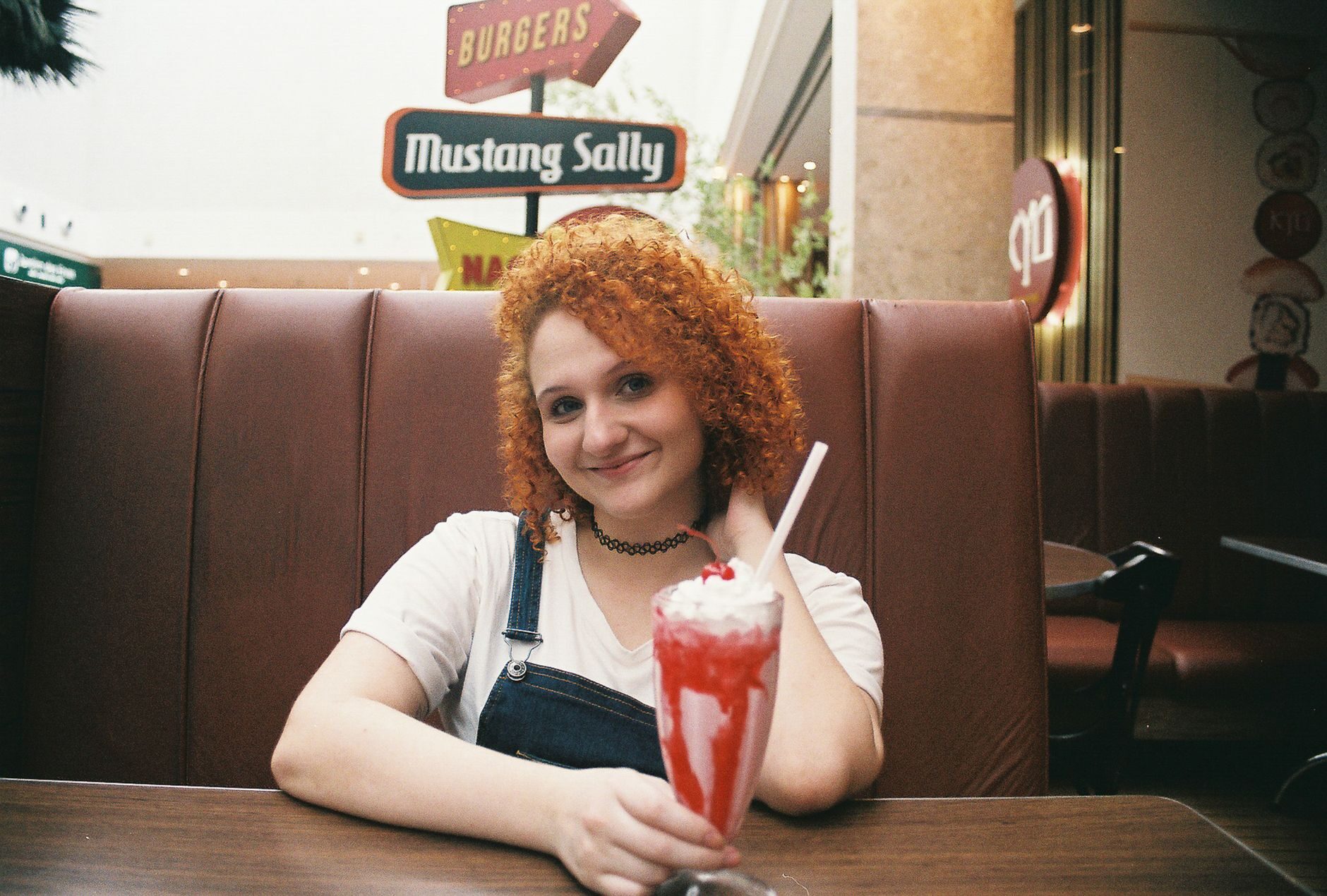 A tall strawberry milkshake in a retro red-leather diner booth.